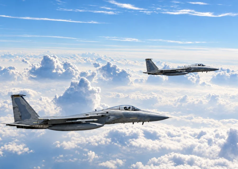 Two F-15 fighter jets flying in formation above the clouds