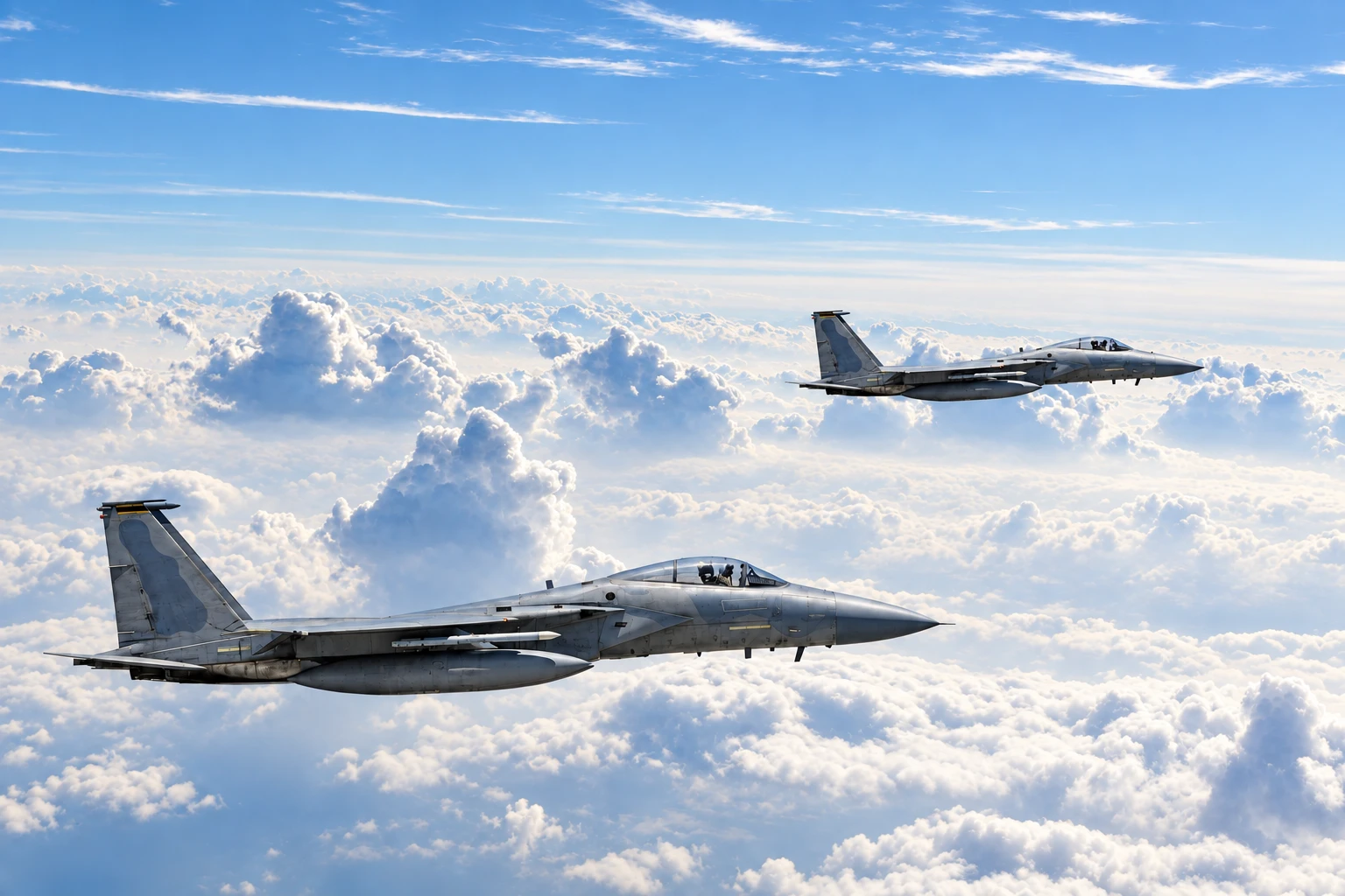 Two F-15 fighter jets flying in formation above the clouds
